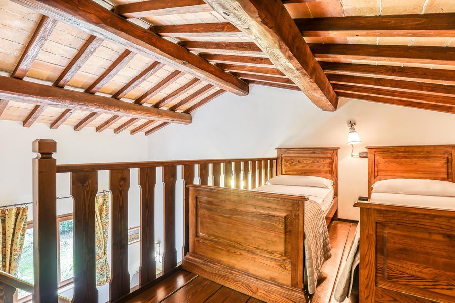 Soppalco mansardato con la ringhiera in legno e due letti singoli