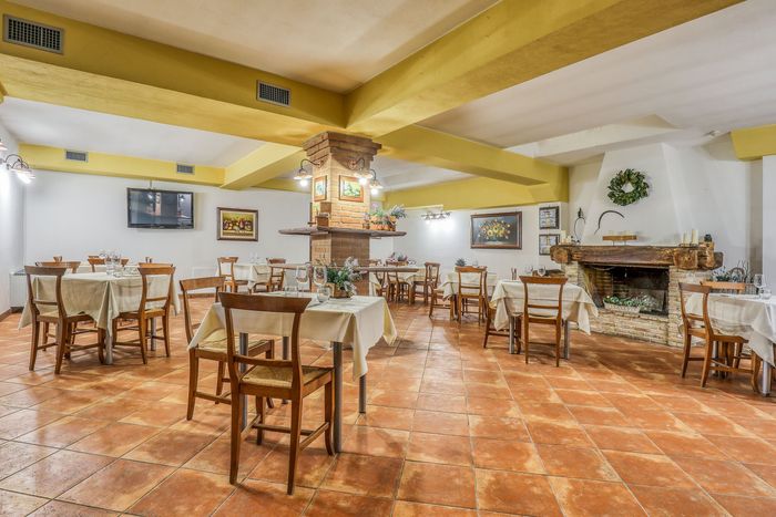 La sala del ristorante con il camino in mattoni, la ghirlanda verde e i tavoli apparecchiati